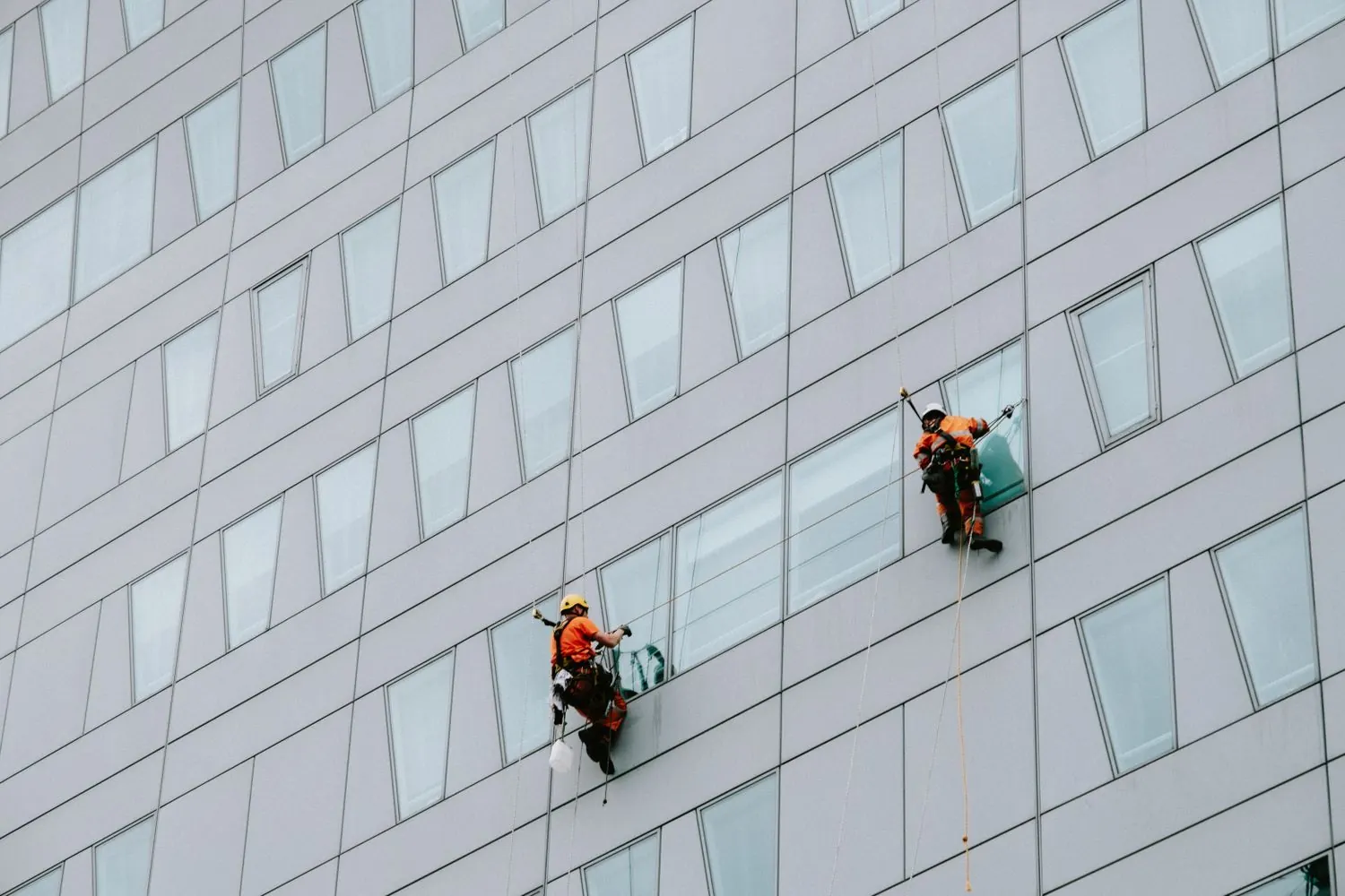 High-rise exterior workers cleaning or repairing a building facade